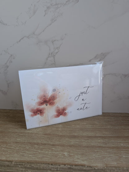 Note card with red watercolor floral design and 'just a note' text on a marble background