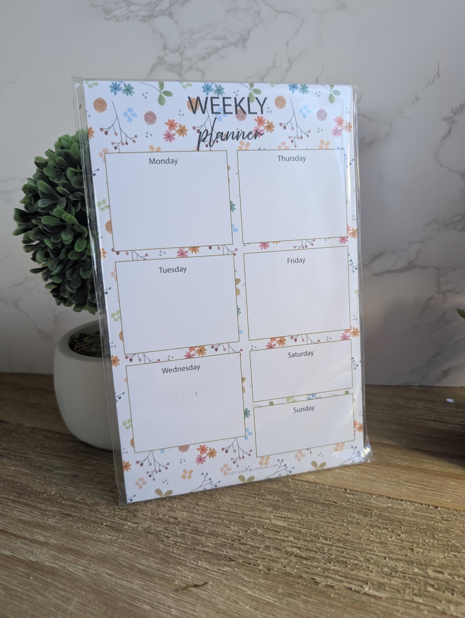 Weekly planner with floral design on a wooden surface