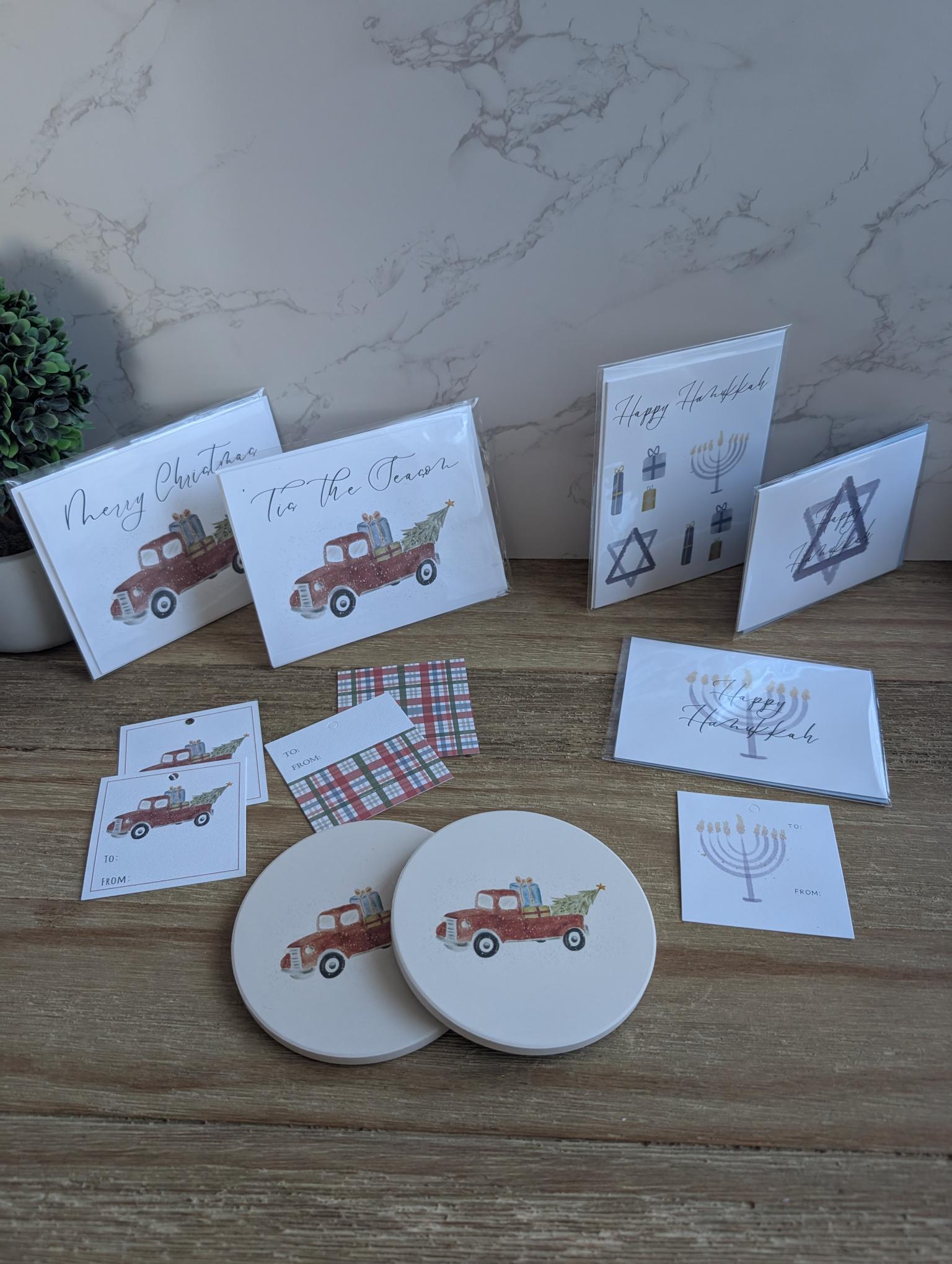 Collection of greeting cards and coasters with festive designs on a wooden surface.