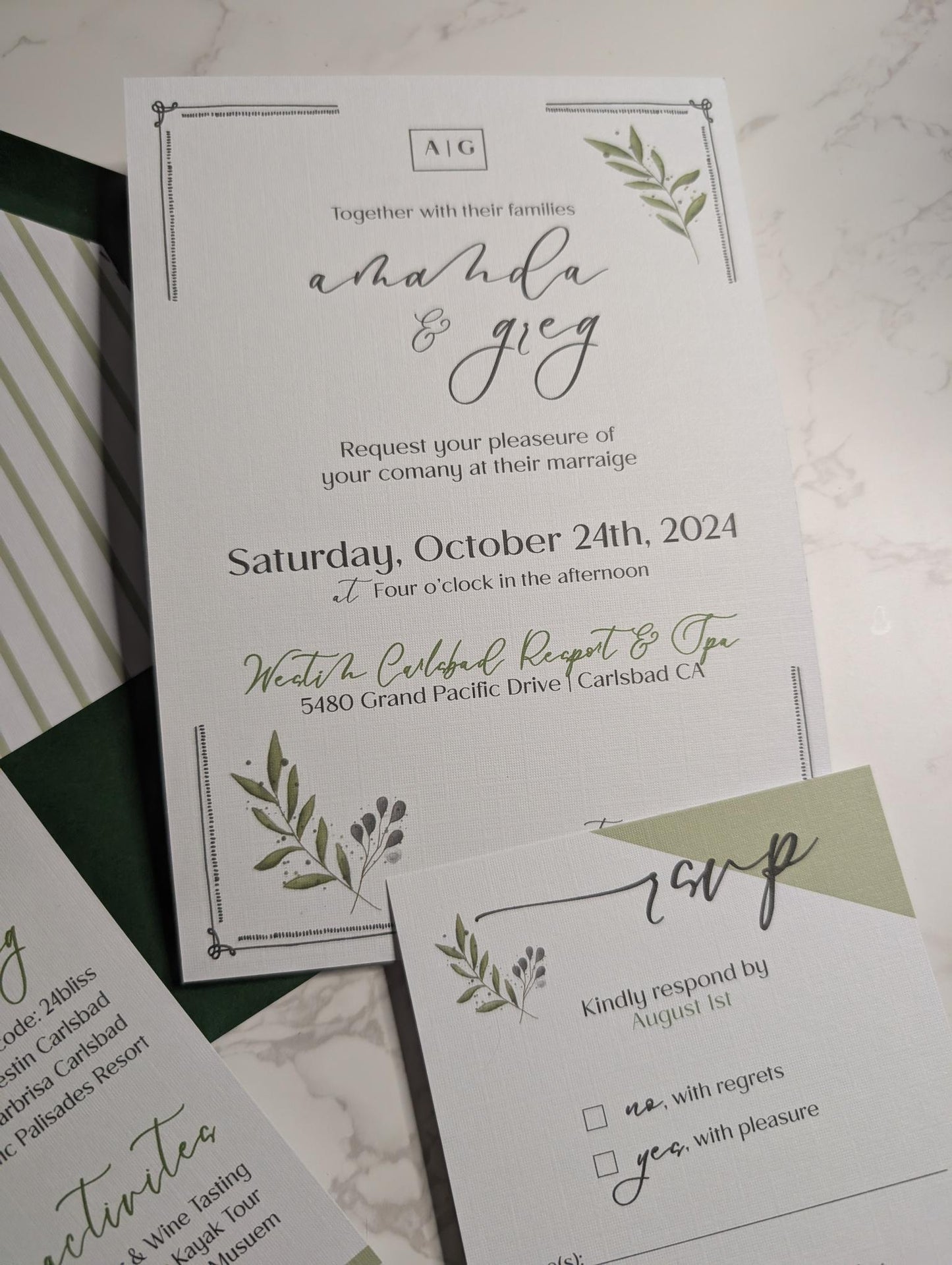 Wedding invitation card with greenery design on a marble surface