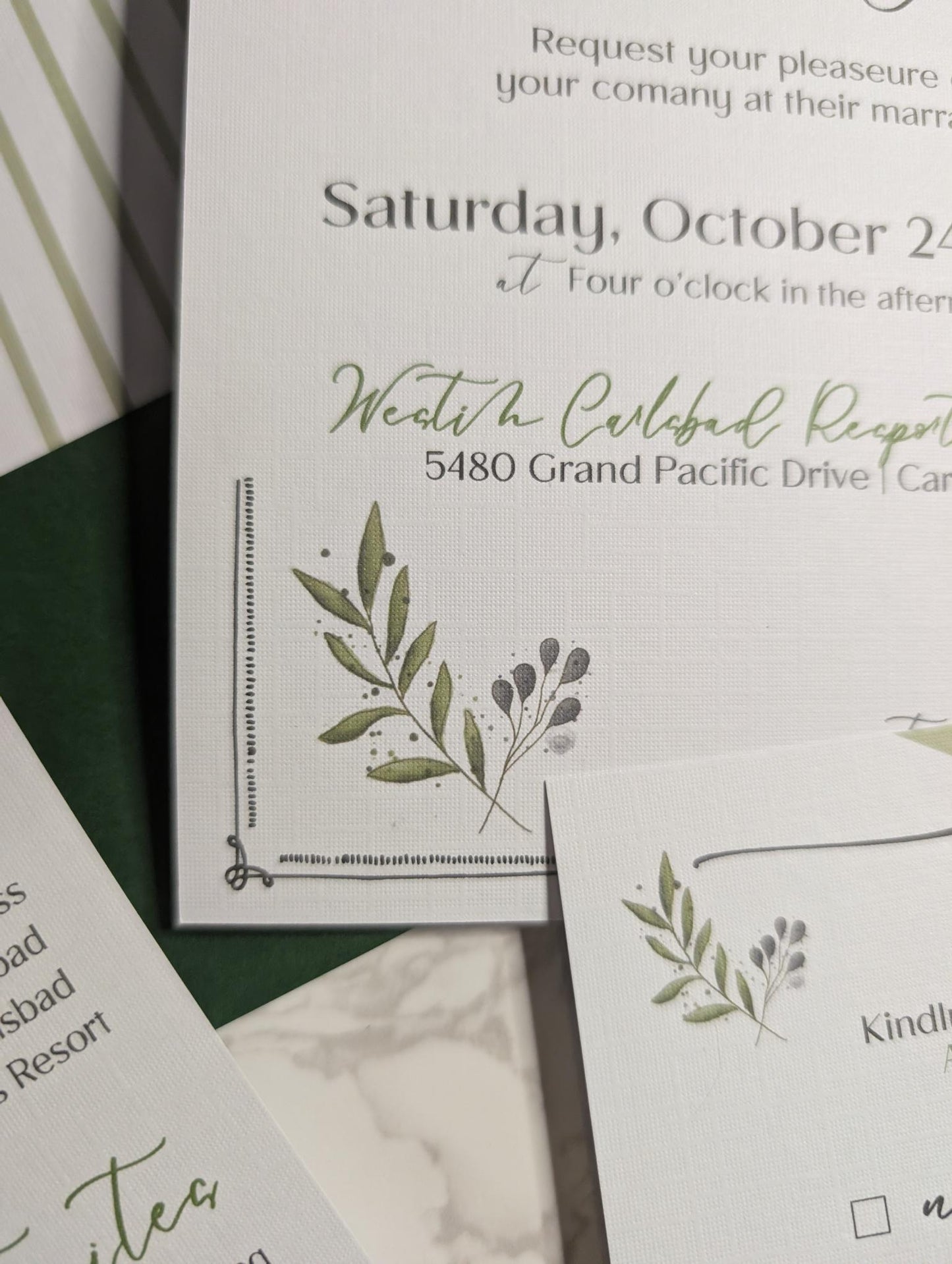 Wedding invitation with greenery design and text on a white background