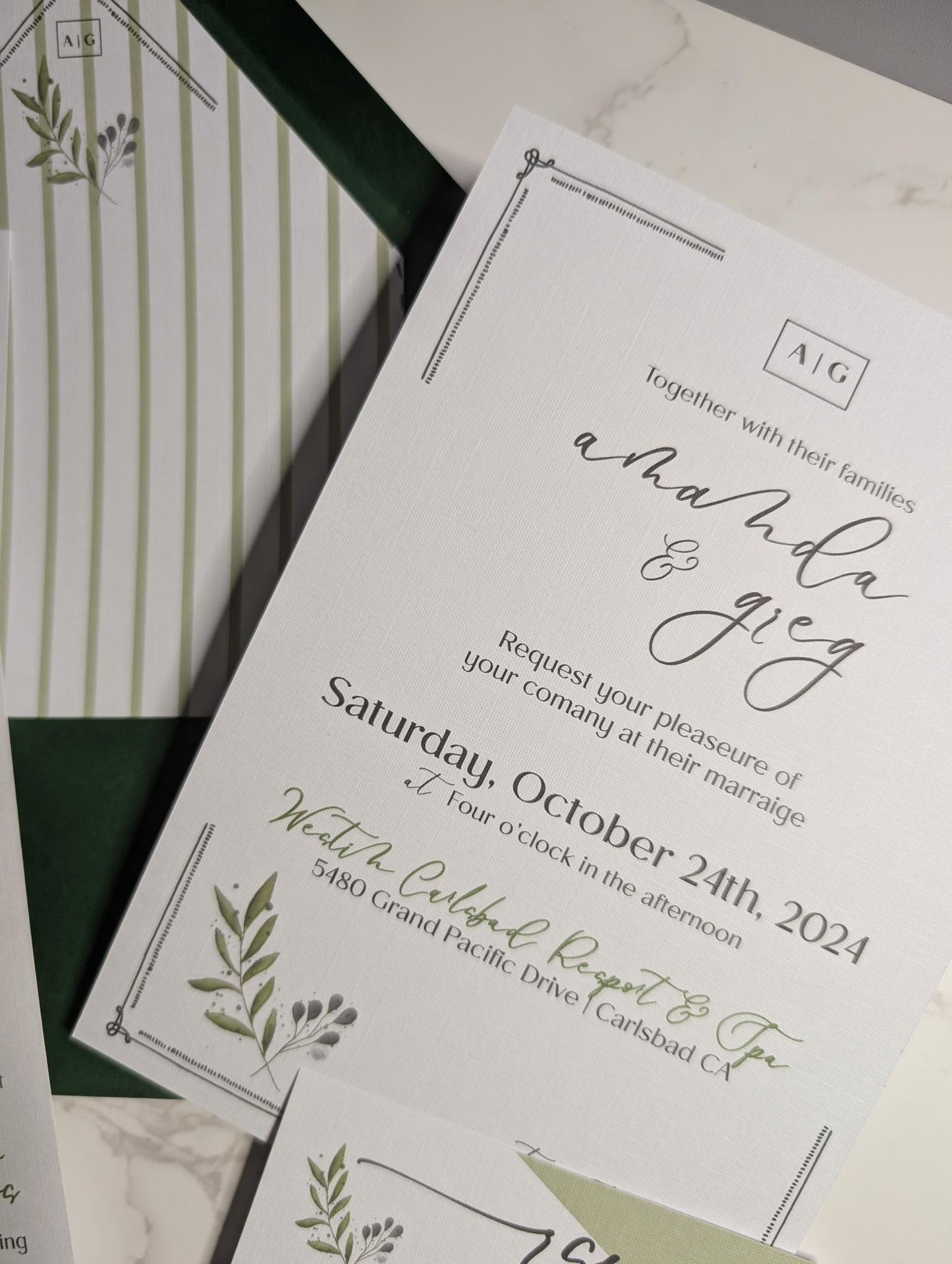Wedding invitation card with greenery design on a white surface