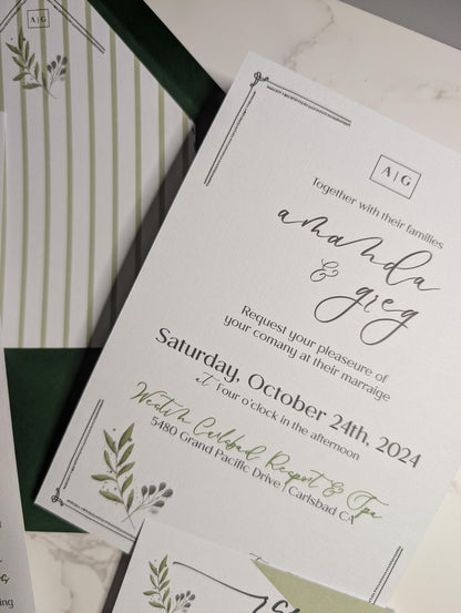 Wedding invitation card with greenery design on a white surface