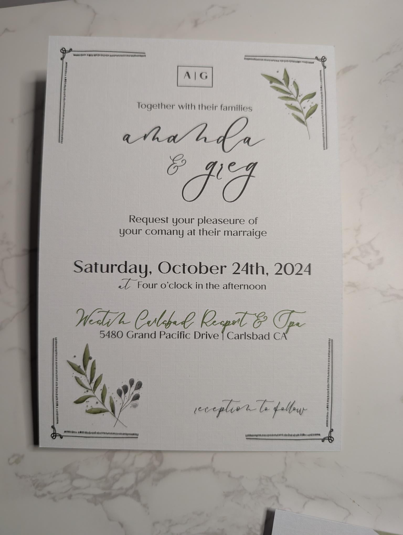 Wedding invitation card with greenery design on a marble surface