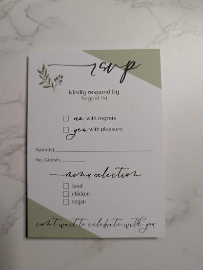 Wedding RSVP card with green accents on a marble surface
