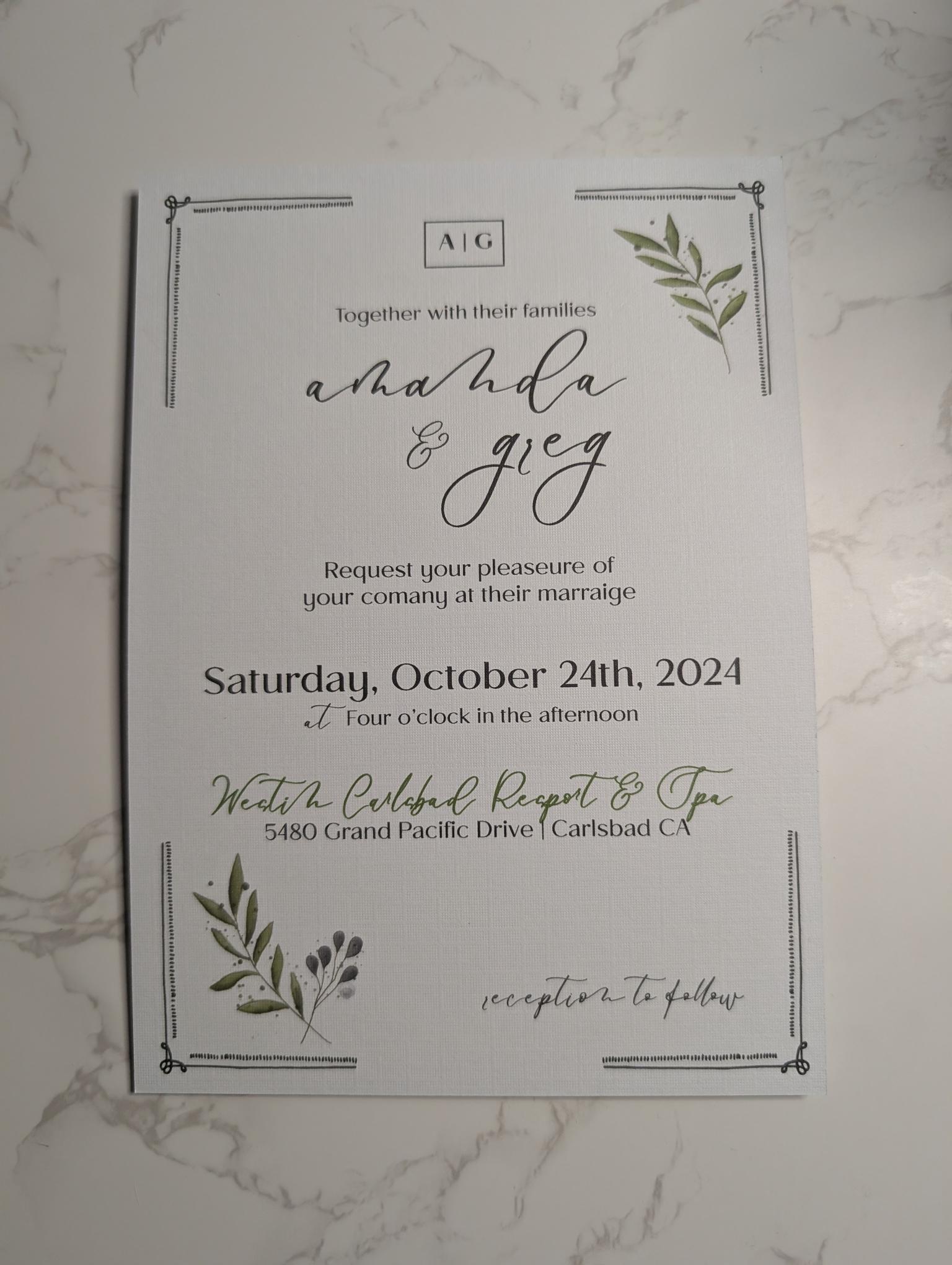 Wedding invitation card with greenery on a marble surface
