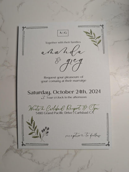 Wedding invitation card with greenery on a marble surface