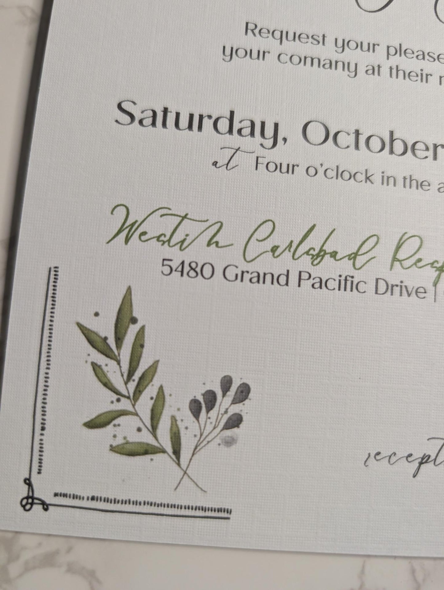 Wedding invitation with greenery design on a marble surface