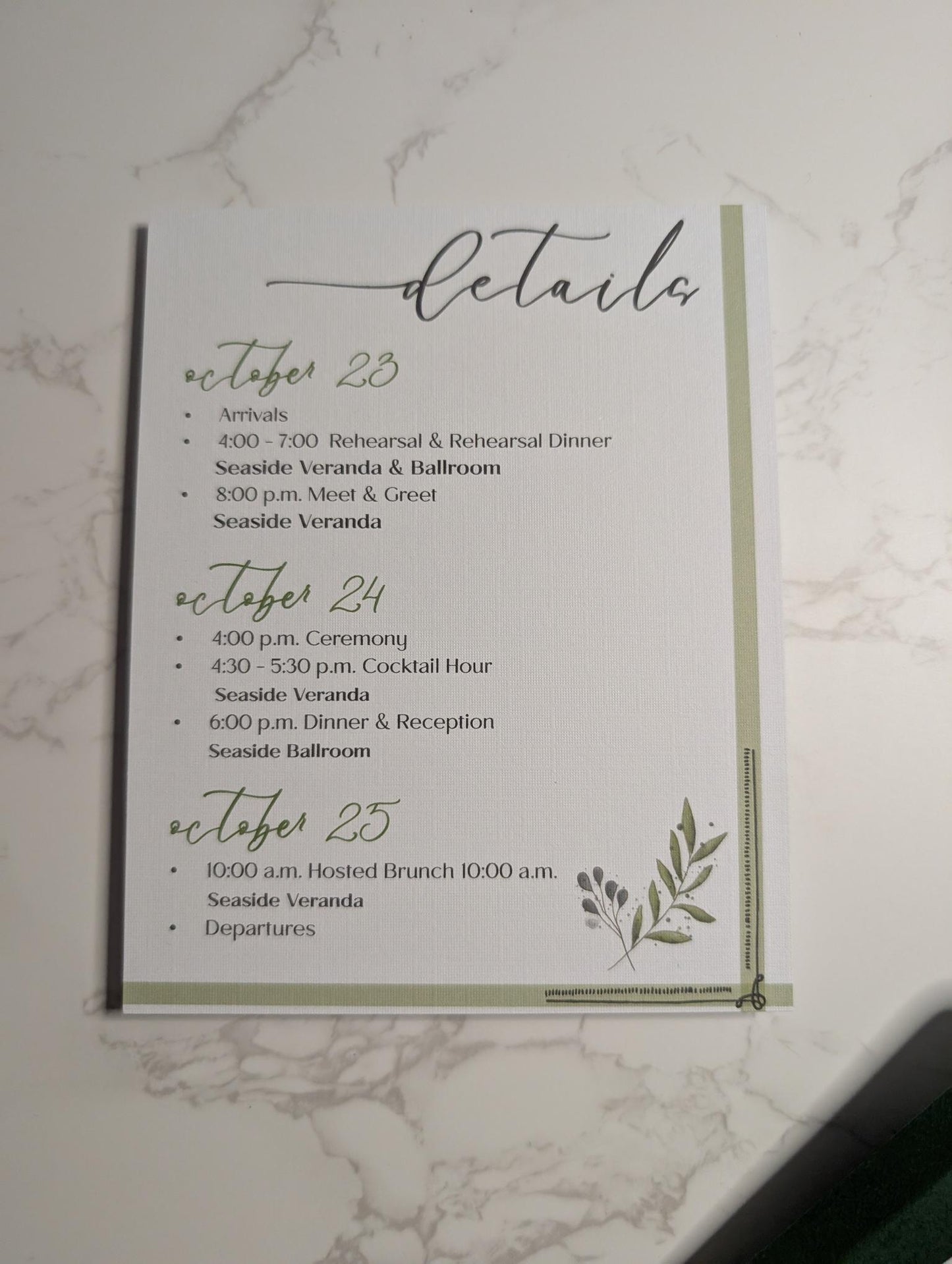 Wedding event details card with a leaf design on a marble background