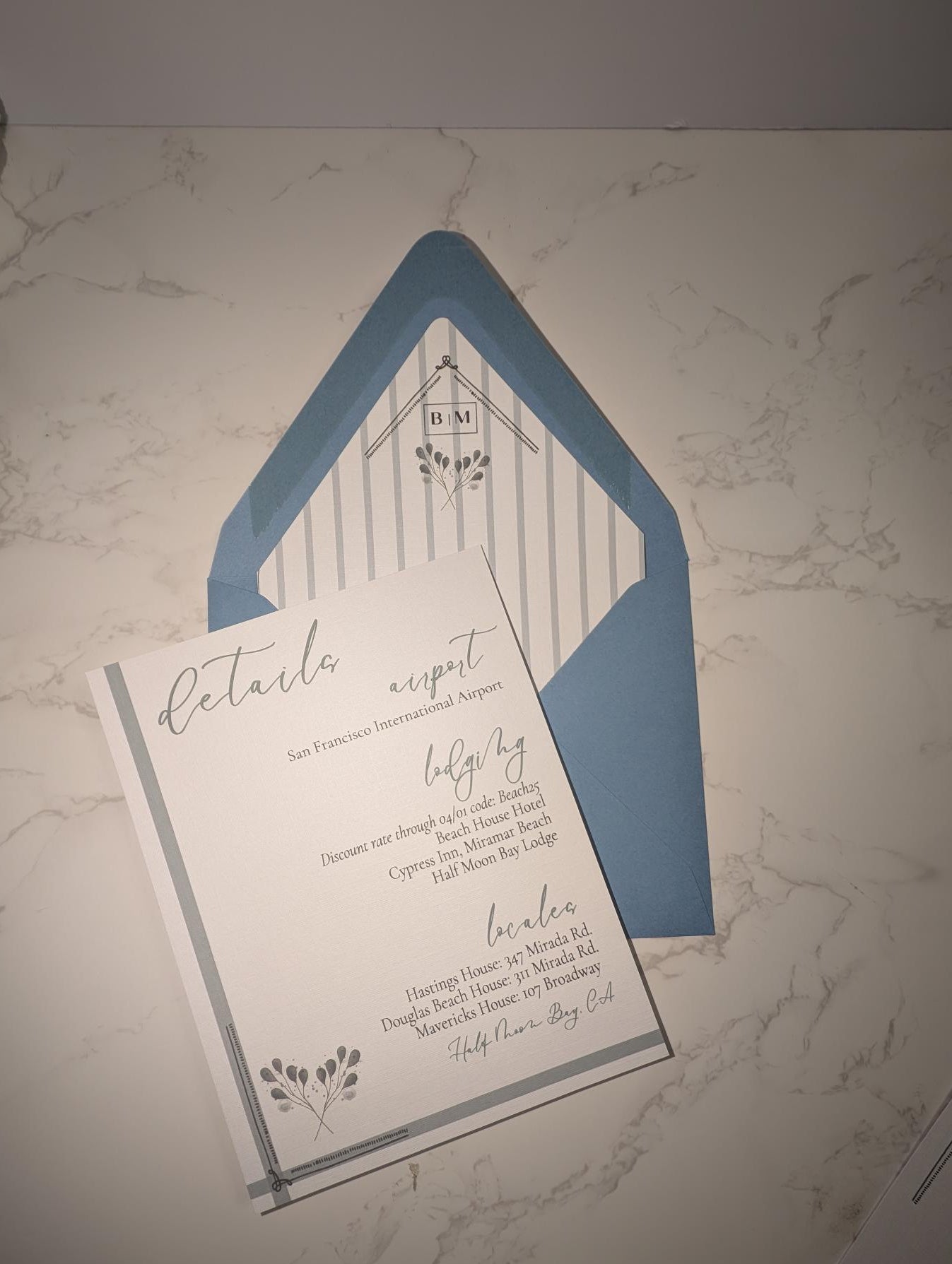 Wedding invitation with blue envelope on a marble surface