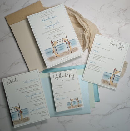 Set of beach-themed wedding invitations on a marble surface