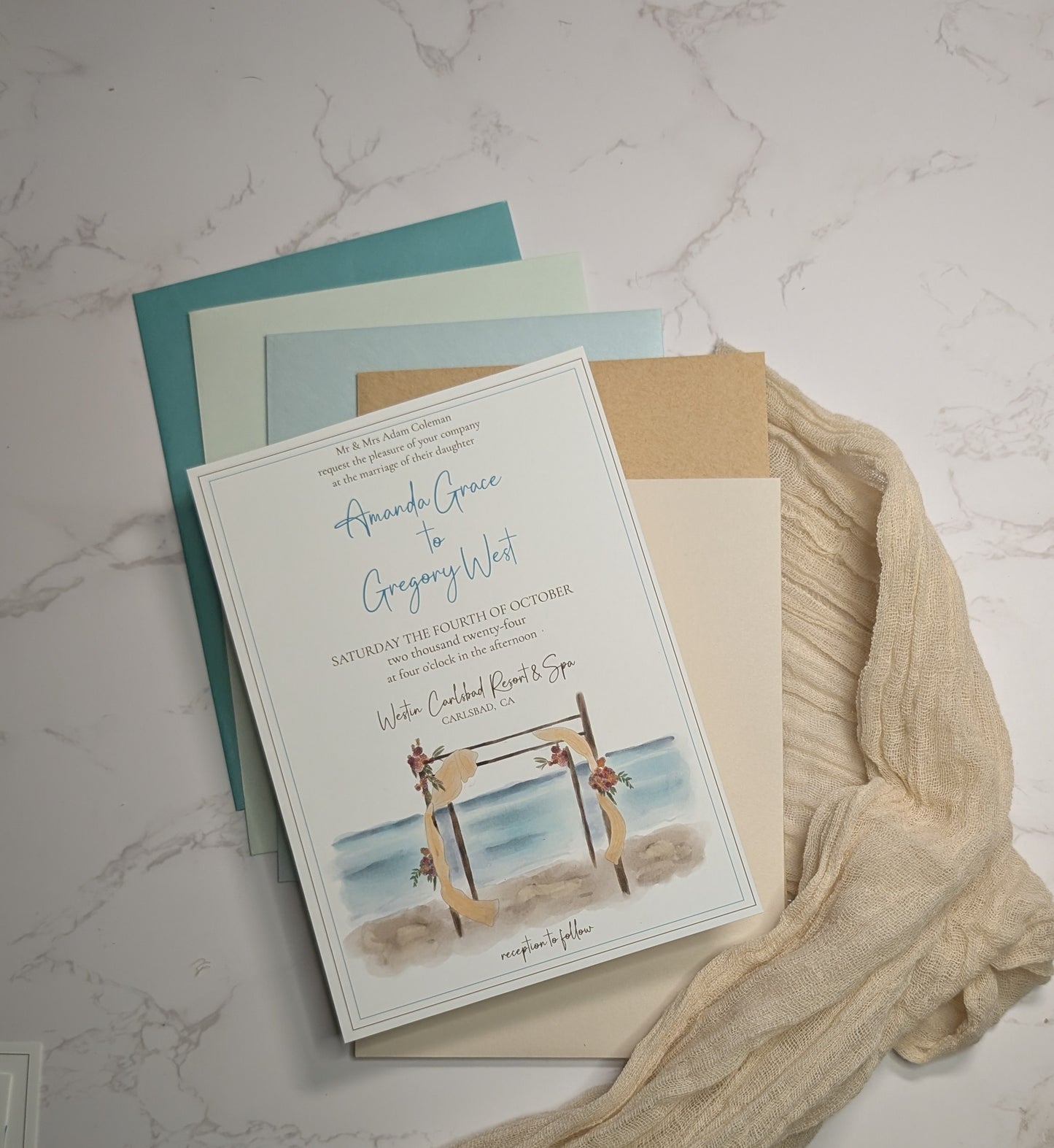 Wedding invitation card with beach scene design on a marble surface