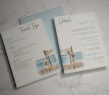 Two wedding invitation cards on a marble surface, one titled 'Travel Info' and the other 'Details'.