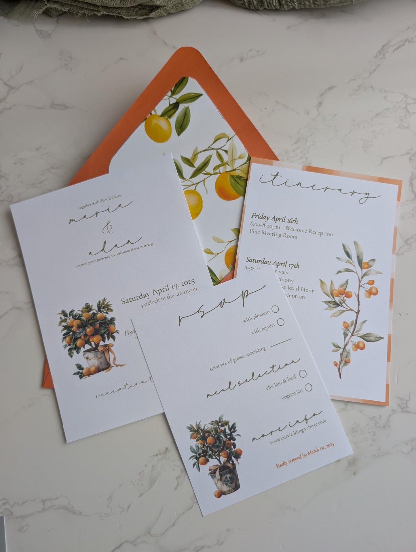 Set of wedding invitations with orange-themed design on a marble surface