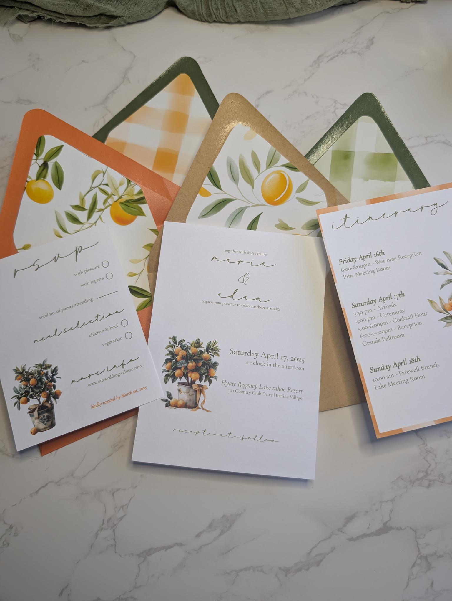 Set of wedding invitations with floral and citrus designs on a marble surface