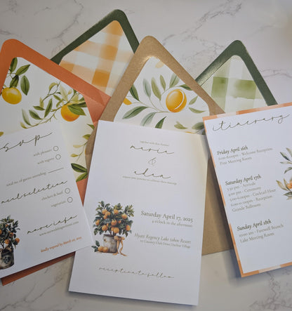 Set of wedding invitations with orange-themed design on a marble surface