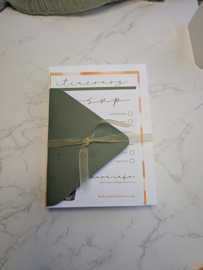 Green envelope with a gold ribbon on a white and gray marble surface