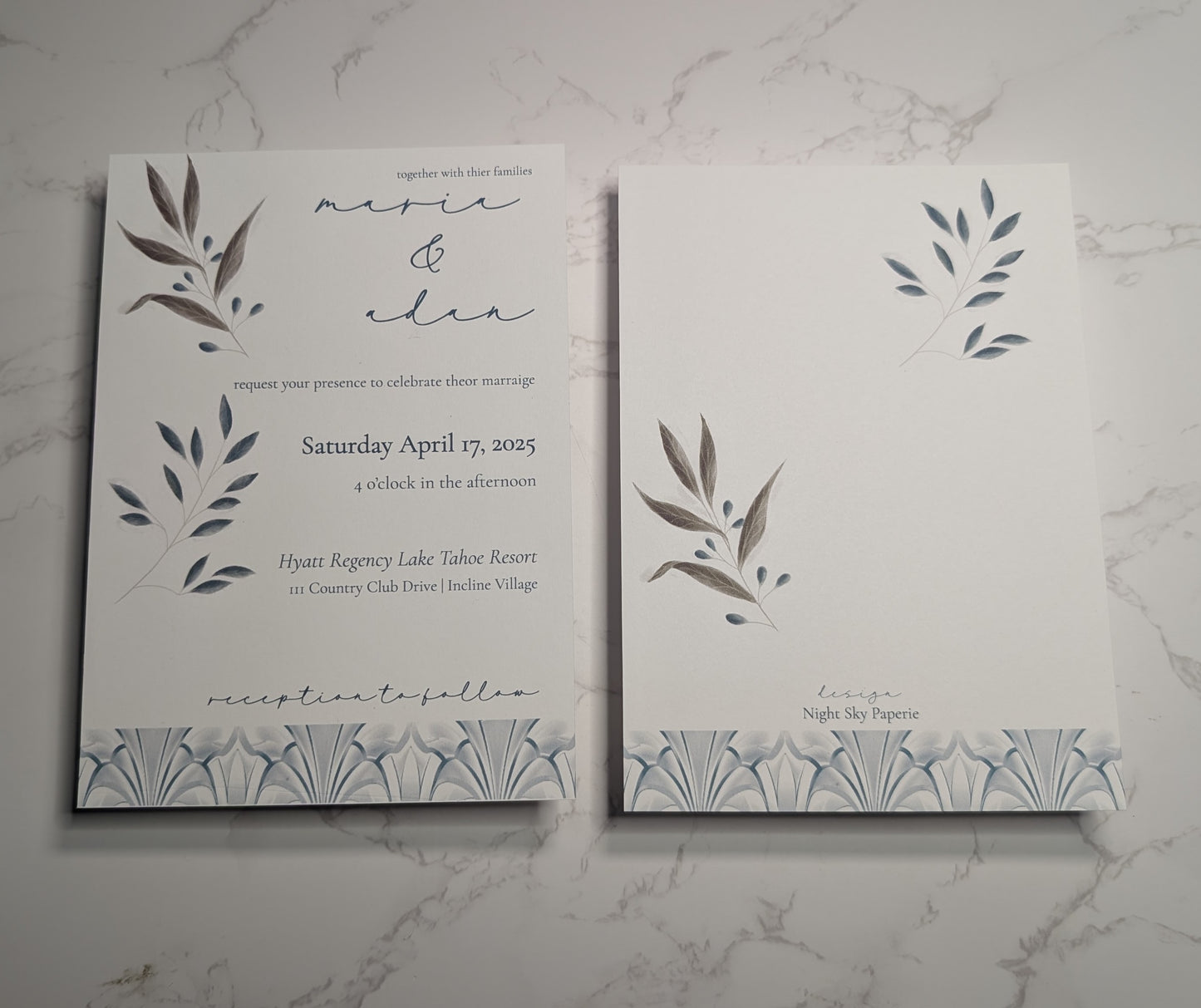 Wedding invitation card with leaf designs on a marble surface