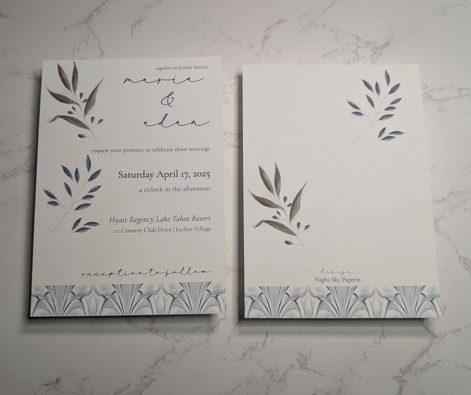 Wedding invitation card with leaf designs on a marble surface