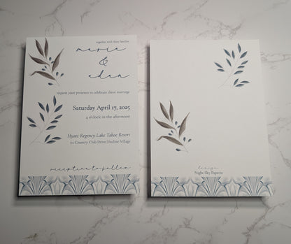 Wedding invitation card with leaf designs on a marble surface