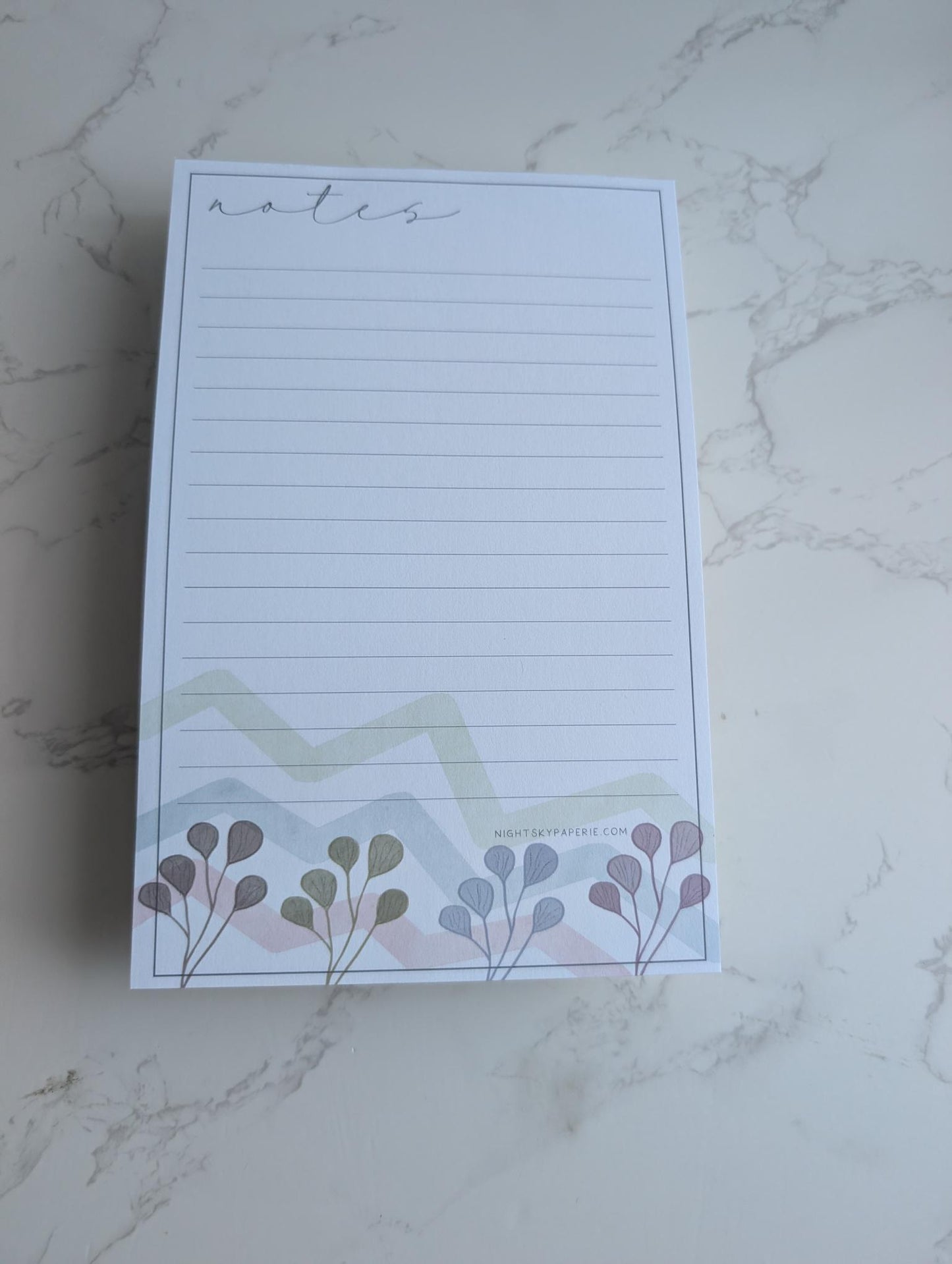 Notepad with floral design on a marble surface