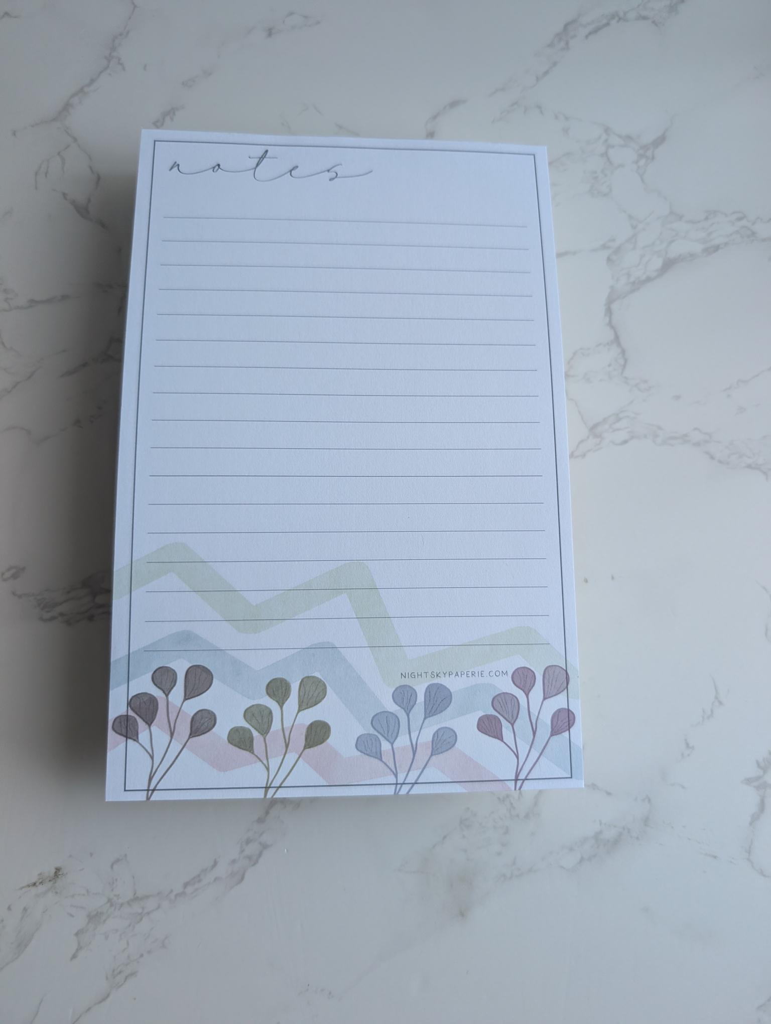 Notepad with floral design on a marble surface