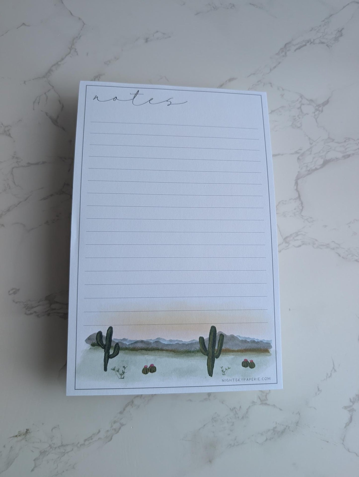 Notepad with cactus design on a marble surface