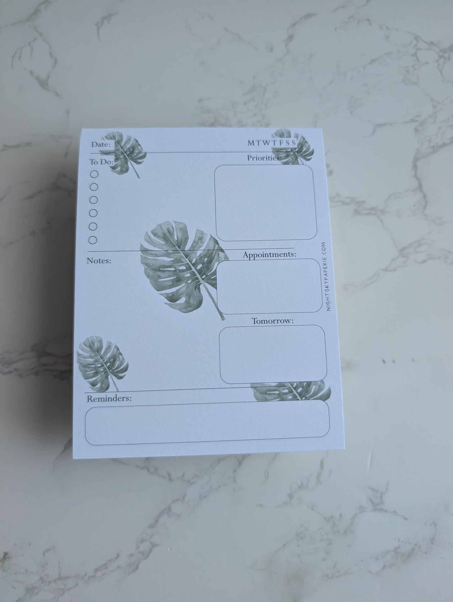Notepad with plant designs on a marble surface