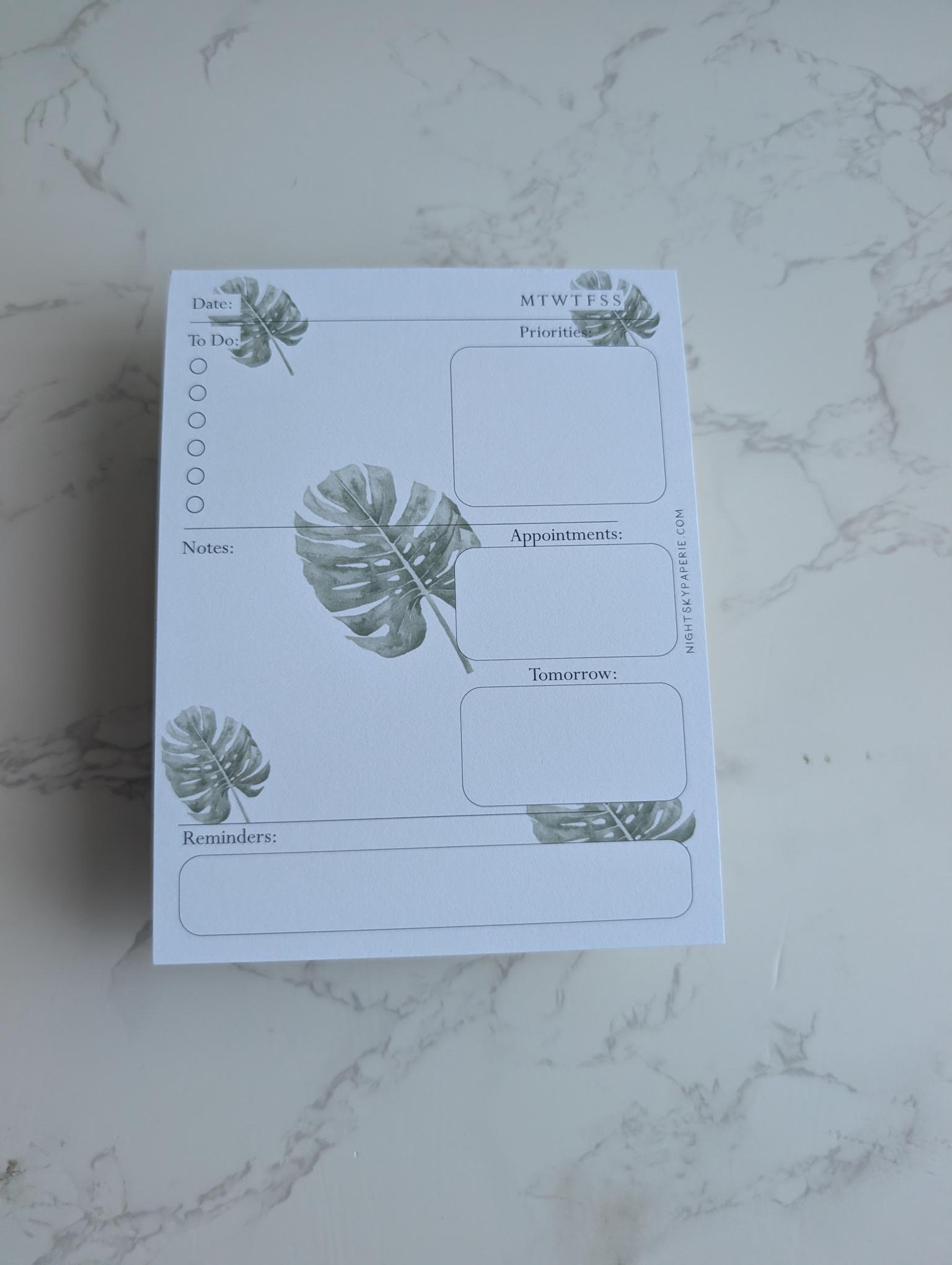 Notepad with plant designs on a marble surface