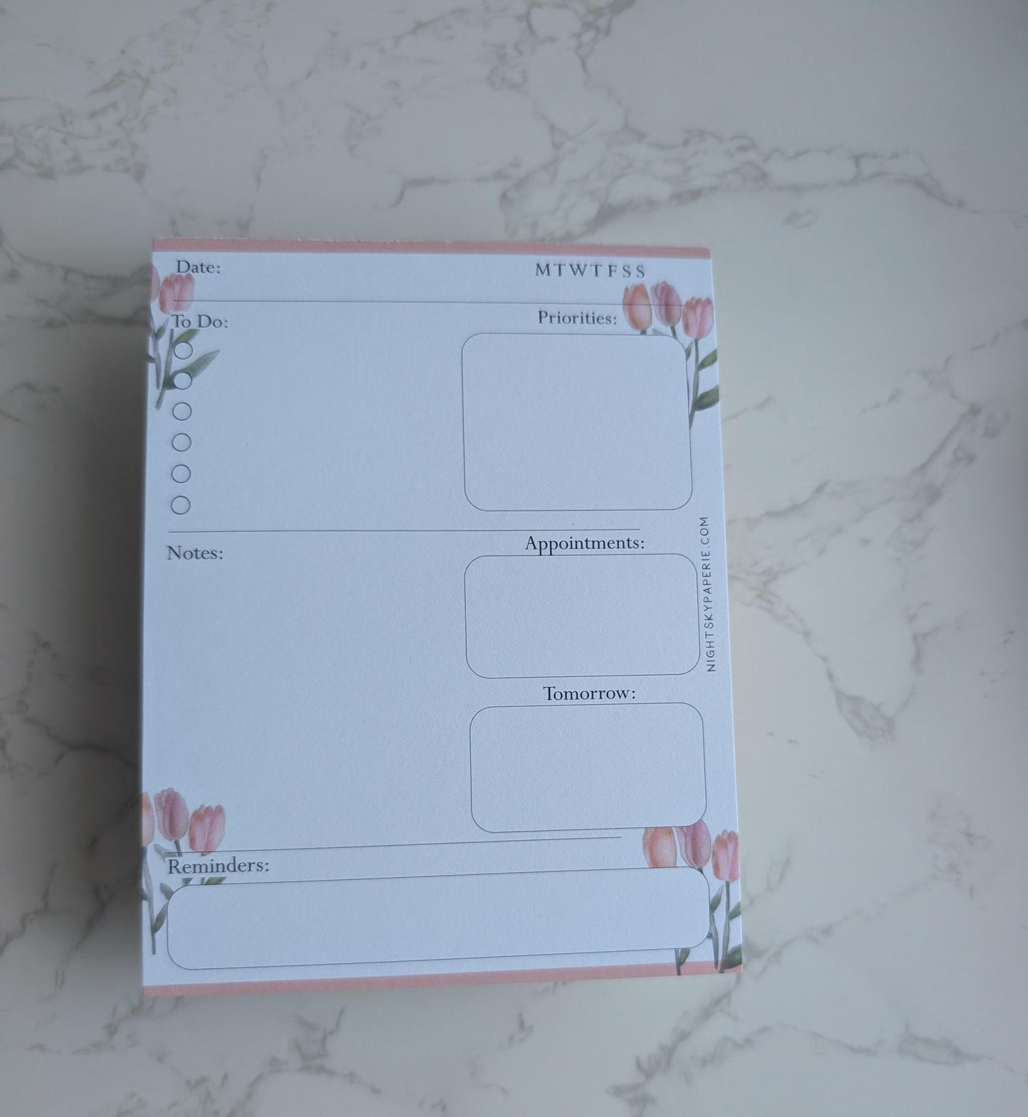 Planner pad with floral design on a marble surface