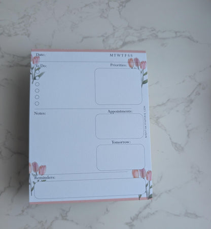 Planner pad with floral design on a marble surface
