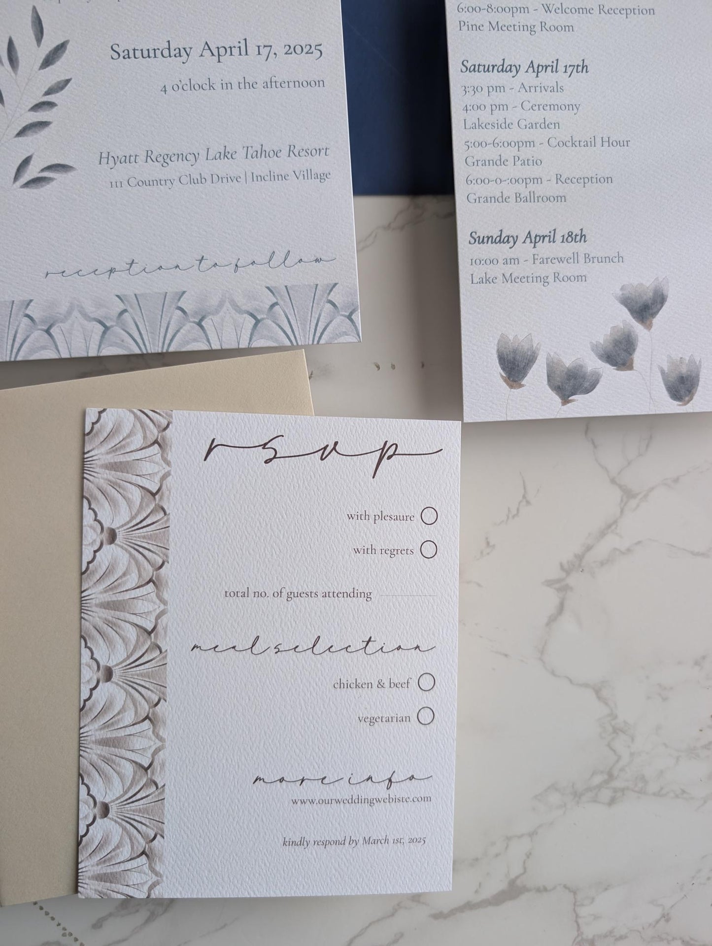 Set of wedding invitations and RSVP card on a marble surface