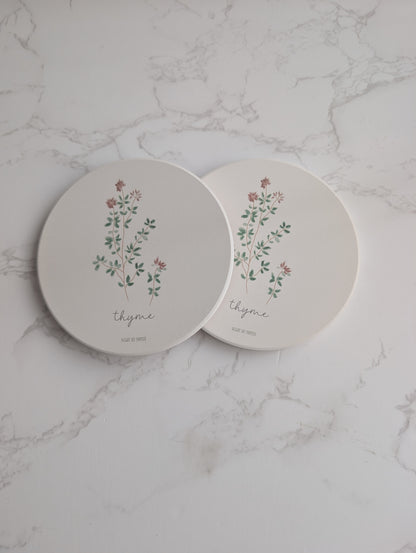 Two round ceramic plates with floral designs and the word 'thyme' on a marble surface.