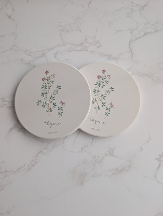 Two round ceramic plates with floral designs and the word 'thyme' on a marble surface.