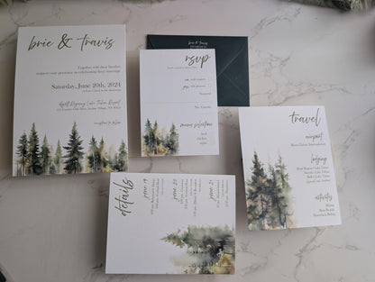 Set of wedding invitations with forest design on a marble surface
