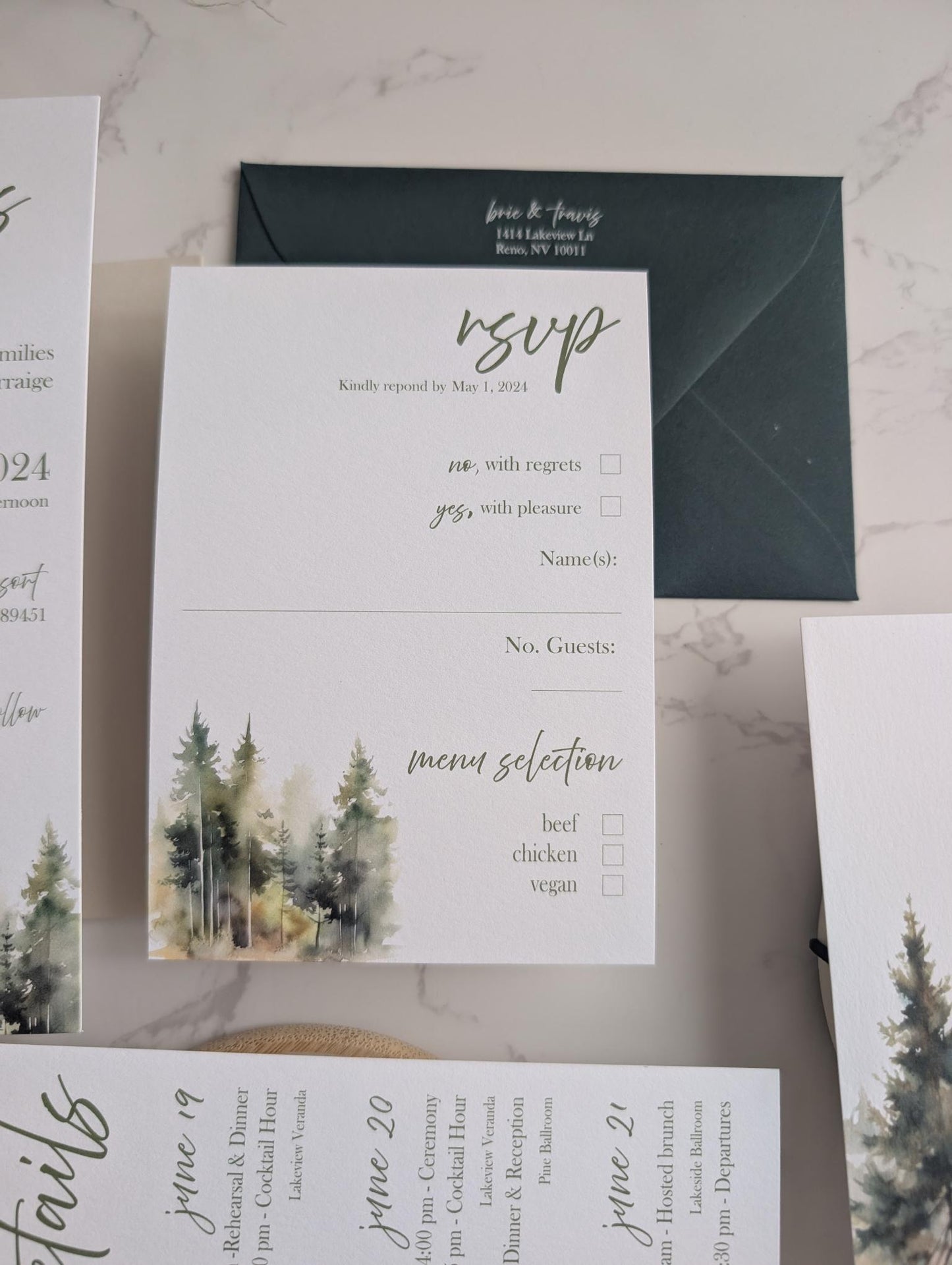 Wedding invitation set with envelope, RSVP card, and menu on a marble surface.