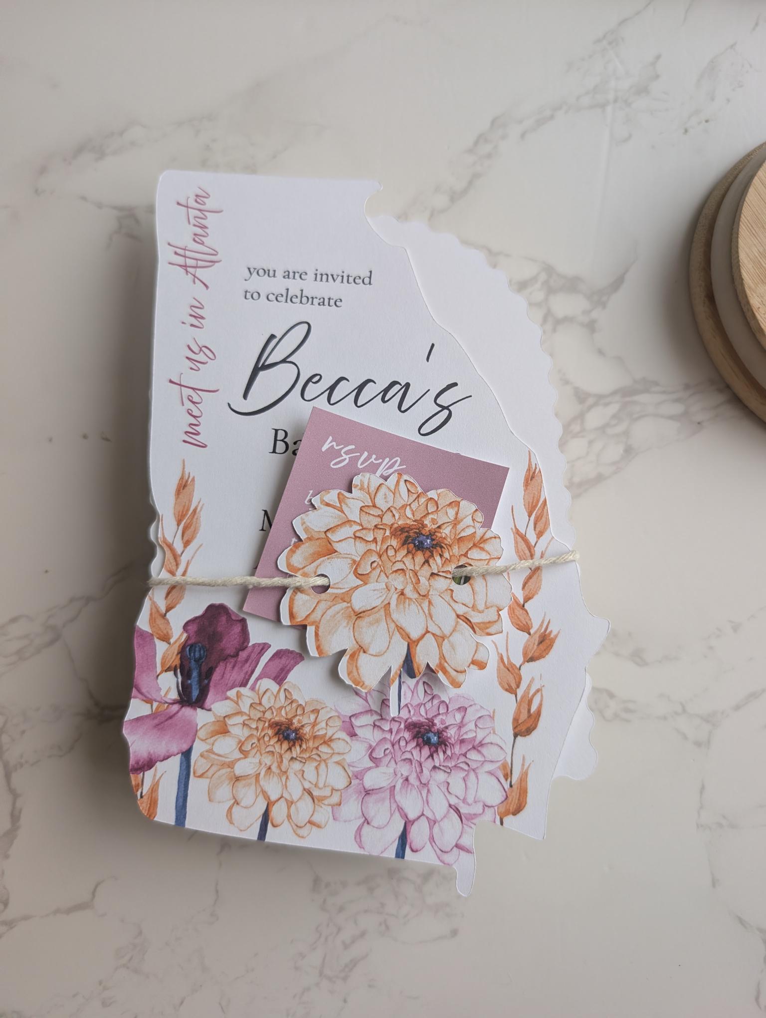 Floral invitation card with a small card attached on a marble surface