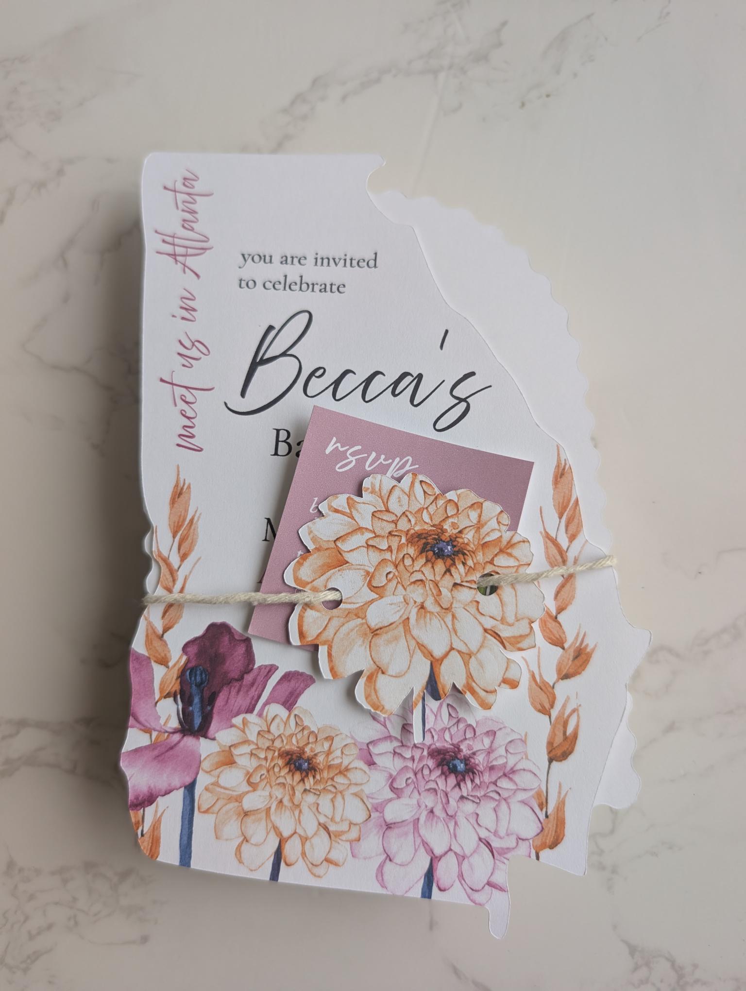 Floral invitation cards tied together on a marble surface