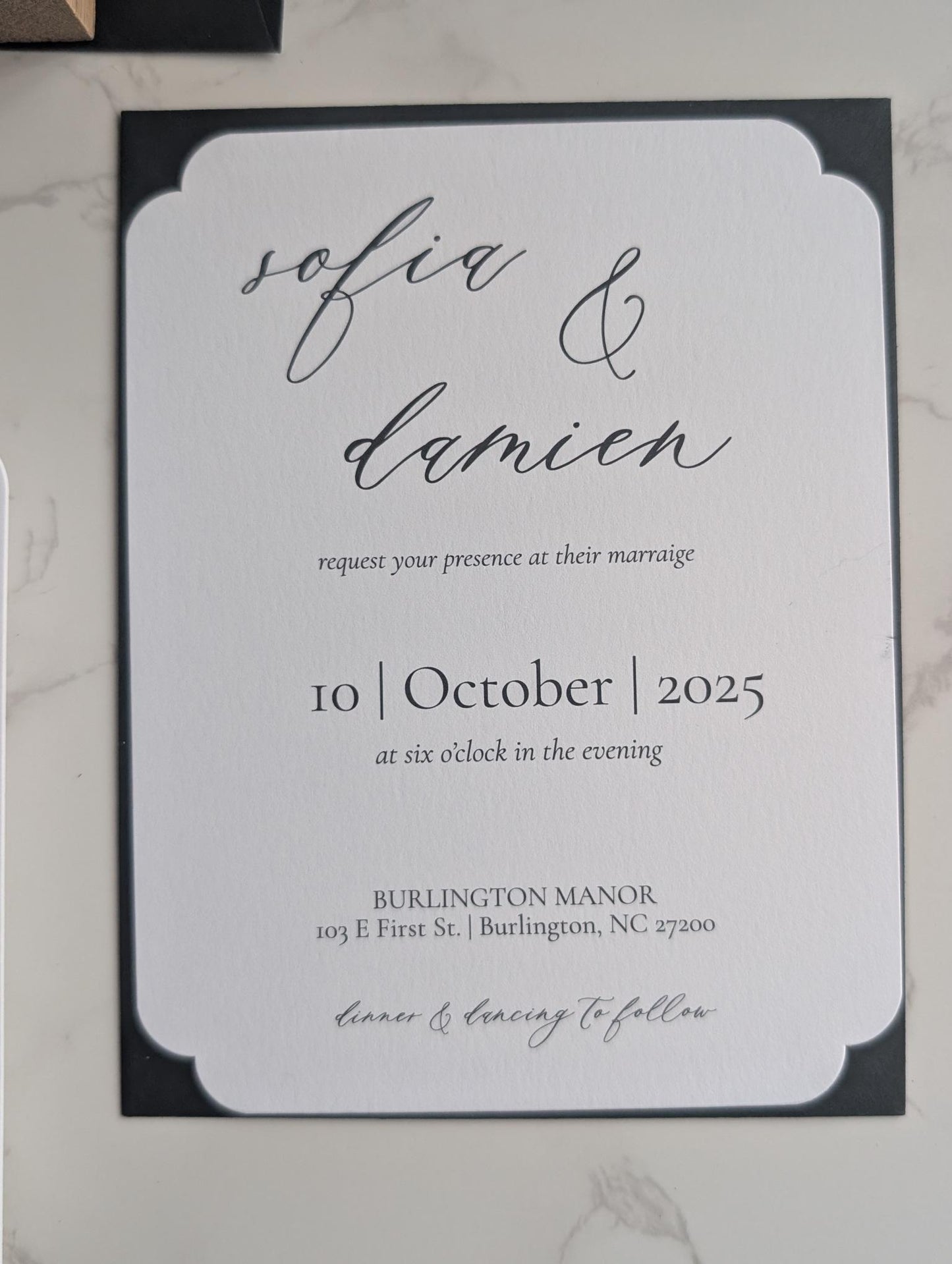 Wedding invitation card with 'sofia & damien' and event details on a marble surface.