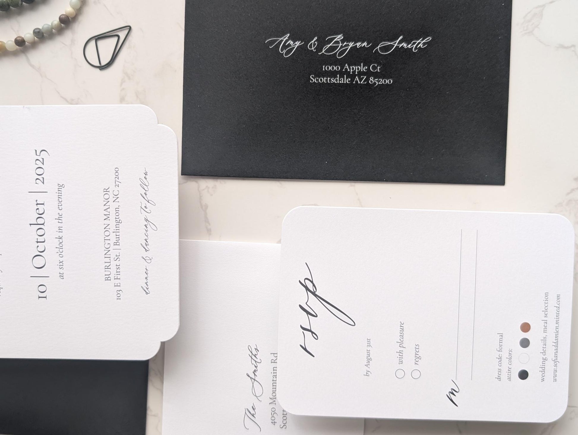 Black and white wedding invitation set on a marble surface