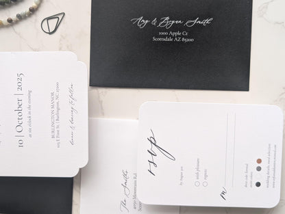 Black and white wedding invitation set on a marble surface
