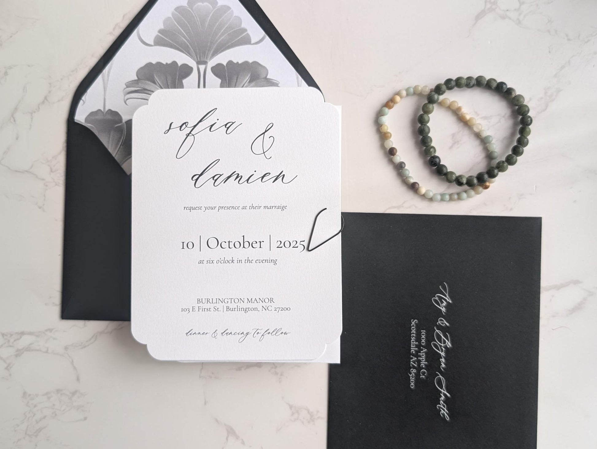 Wedding invitation card with envelope and bracelet on a marble surface