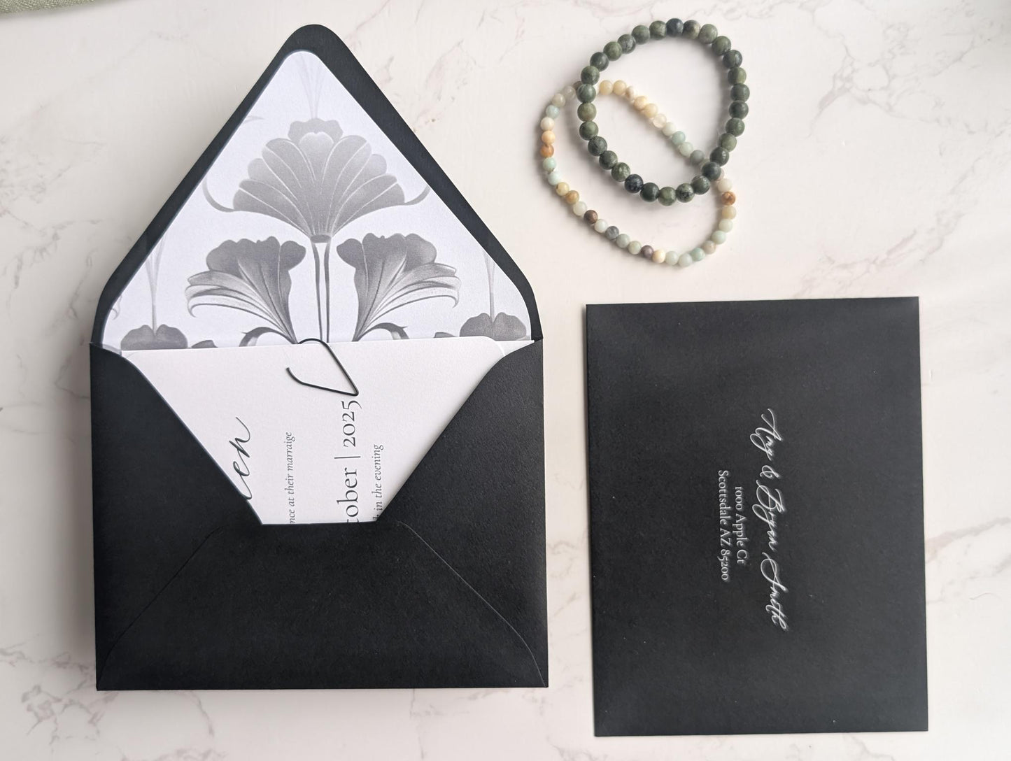 Black envelope with white interior design and card on a light surface