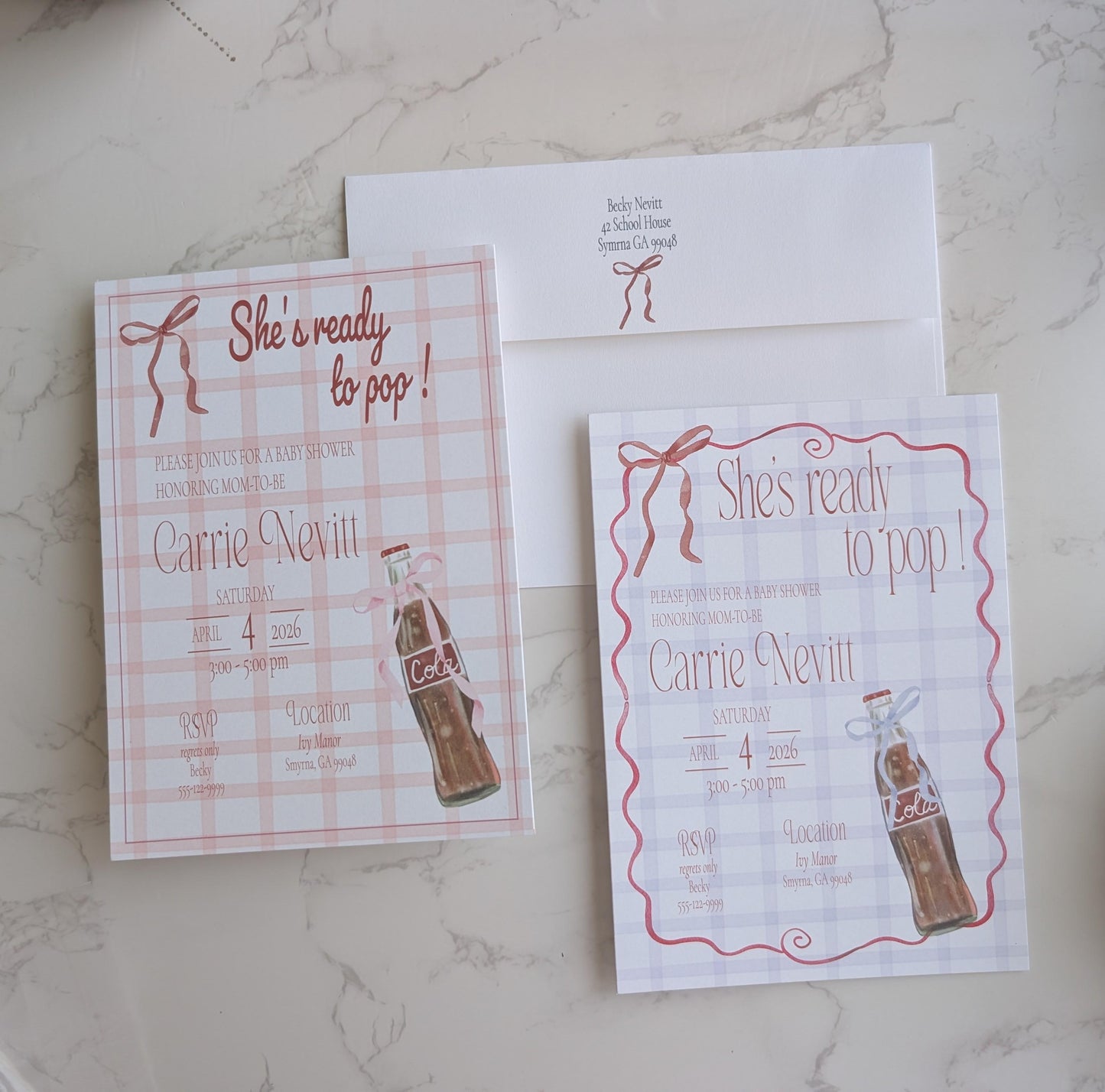 A flat-lay of a matching bridal shower invitation suite featuring a pink and white gingham check pattern, red script text, and an illustration of a vintage Coca-Cola bottle, shown with an envelope on a light marble surface.