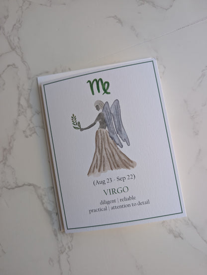 A rectangular white card featuring a watercolor-style Virgo angel illustration and the text 'Me (Aug 23 - Sep 22) VIRGO diligent | reliable | practical | attention to detail', photographed on a light marble surface.