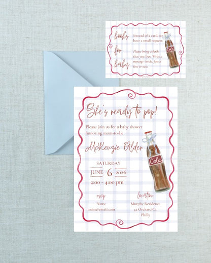 A baby shower invitation card with a matching envelope on a light blue textured background. The invitation features a white and light blue gingham pattern, pink decorative borders, and a retro cola bottle illustration with the word 'Cola'.