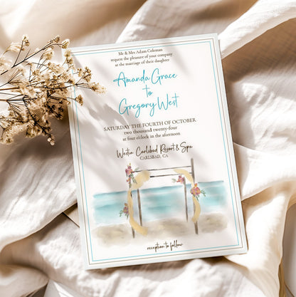 Wedding invitation card with beach scene design on a white fabric background