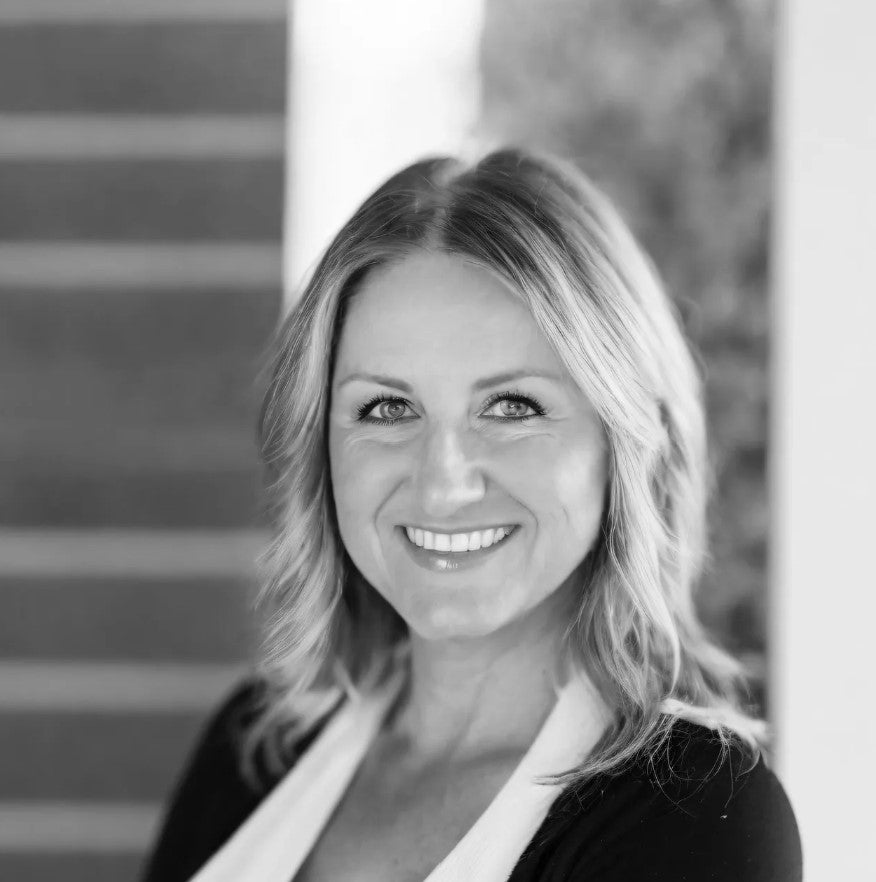 Black and white photo of a woman with blonde hair smiling outdoors.