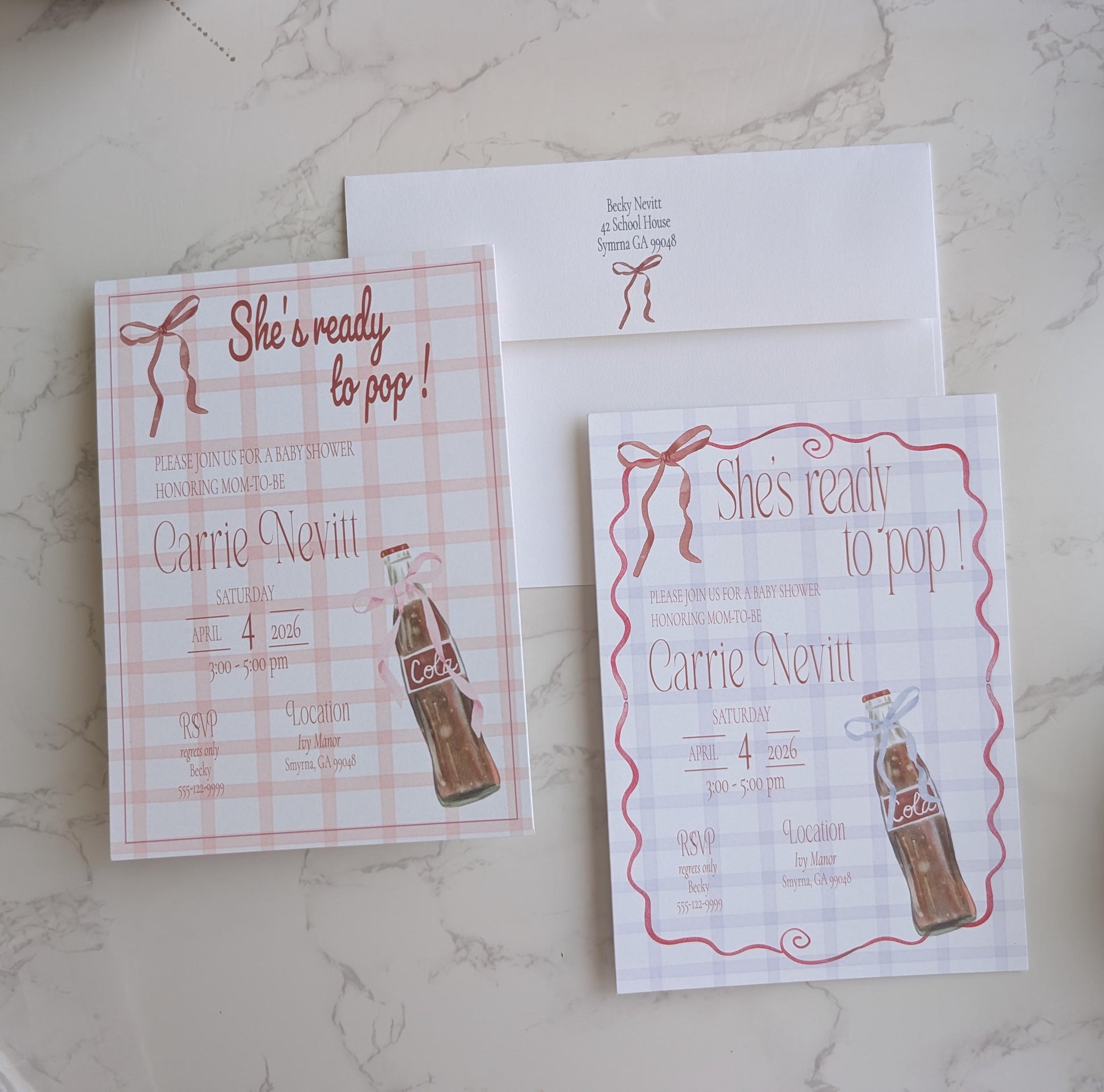 A flat-lay of a matching bridal shower invitation suite on a light marble surface, featuring a pink and white gingham check invitation card, a white envelope with pink script text, and a second invitation with a pink wavy border.