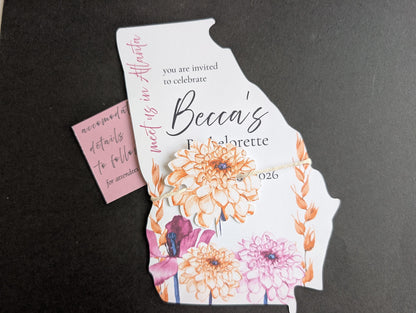 Invitation card shaped like the state of Georgia with floral design on a black background